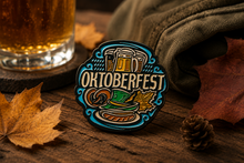 Oktoberfest-themed pin on a wooden surface with a glass of beer and fall leaves.