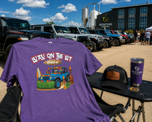 A purple heather graphic t-shirt with 'L'AU ON THE LOT CRUISE-IN' and a jeep illustration, displayed outdoors 