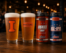 Two glasses of beer and two cans of DESTIHL beer on a wooden surface with a blurred bar background.