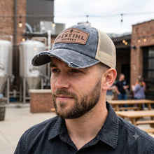 Man wearing a DESTIHL Brewery cap outdoors with brewing equipment in the background